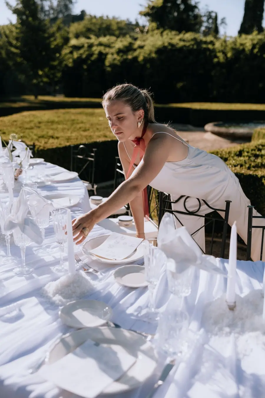 Preparando una mesa de boda en un jardín, plato a plato